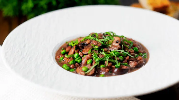 Pearl barley risotto or orzotto with red wine, mushrooms and sweet green peas.
