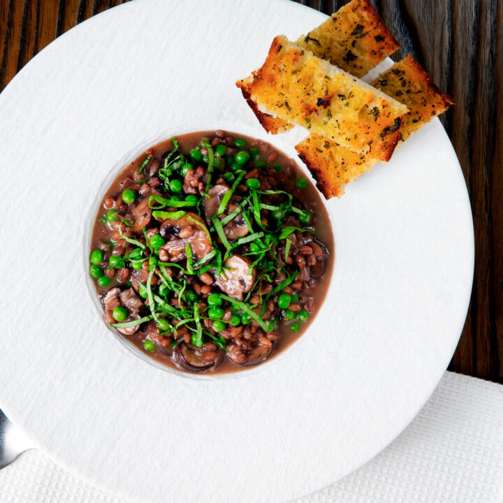 Pearl barley risotto or orzotto with red wine, mushrooms and sweet green peas.