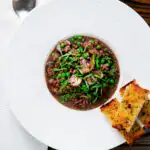 Overhead mushroom pearl barley risotto or orzotto cooked with red wine and peas.