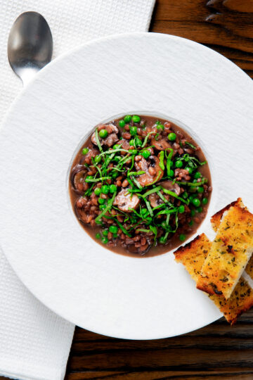Overhead mushroom pearl barley risotto or orzotto cooked with red wine and peas.