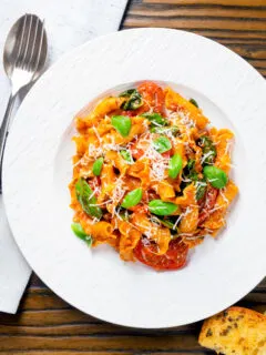 Overhead spicy nduja pasta made with Fiorelli, tomatoes and fresh basil.