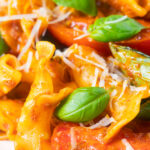 Close-up spicy nduja sausage pasta made with tomatoes and fresh basil.