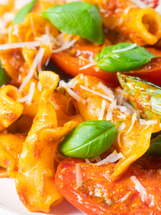 Close-up spicy nduja sausage pasta made with tomatoes and fresh basil.