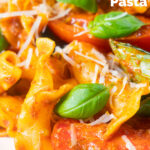 Close-up spicy nduja sausage pasta made with tomatoes and fresh basil featuring a title overlay.