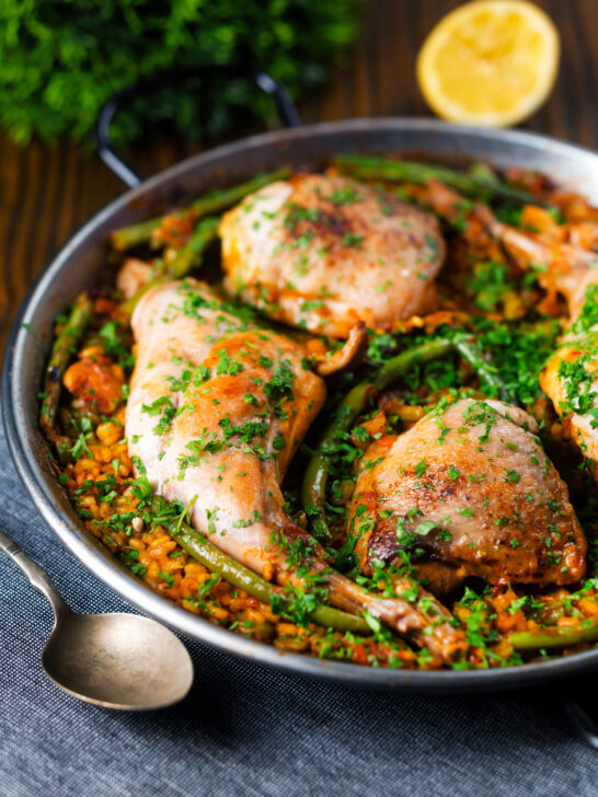 Paella Valenciana with rabbit and chicken presented in a traditional cooking pan.