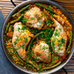 Overhead paella Valenciana with rabbit and chicken presented in a traditional cooking pan.