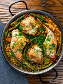 Overhead paella Valenciana with rabbit and chicken presented in a traditional cooking pan.
