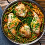 Overhead paella Valenciana with rabbit and chicken presented in a traditional cooking pan featuring a title overlay.