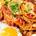Close-up British layered corned beef and potato bake or panacalty with a fried egg.