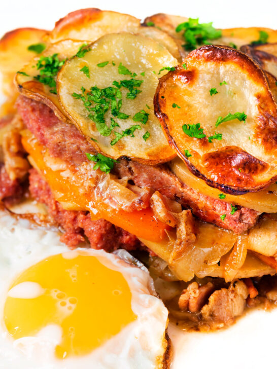 Close-up British layered corned beef and potato bake or panacalty with a fried egg.