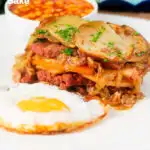 Layered corned beef and potato bake or panacalty with a fried egg and baked beans featuring a title overlay.