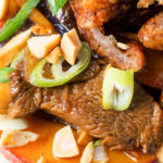 Close-up stir-fried duck breast with fresh plums and crispy skin.
