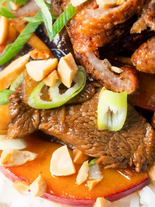 Close-up stir-fried duck breast with fresh plums and crispy skin.