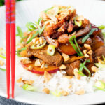 Plum and duck stir fry with crispy skin, toasted peanuts and spring onions featuring a title overlay.