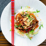 Overhead plum and duck stir fry with crispy skin, toasted peanuts and spring onions.