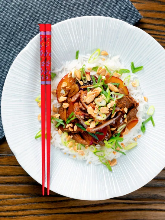 Overhead plum and duck stir fry with crispy skin, toasted peanuts and spring onions.