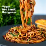 Vegan red lentil bolognese with linguini pasta being picked up with a fork featuring a title overlay.