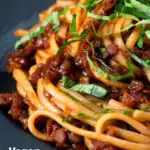 Close-up vegan red lentil ragu with linguini pasta and fresh basil featuring a title overlay.