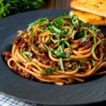 Vegan red lentil bolognese served with fresh basil and garlic bread.