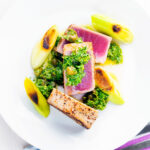 Overhead seared tuna steak with a sauce made from capers, parsley, lemon and olive oil.