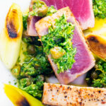 Close-up overhead seared tuna steak with a sauce made from capers, parsley, lemon and olive oil.