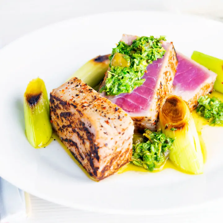 Rare cooked tuna steak with capers, lemon and parsley sauce and seared leeks.