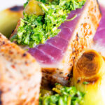 Close-up seared tuna steak with a sauce made from capers, parsley, lemon and olive oil featuring a title overlay.