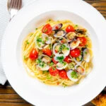 Overhead spaghetti alle vongole or clam pasta with tomatoes, parsley and garlic.