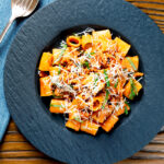 Overhead spicy chicken mince pasta with fresh basil and parmesan cheese.