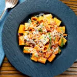 Overhead spicy chicken mince pasta with fresh basil and parmesan cheese.