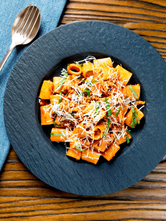 Overhead spicy chicken mince pasta with fresh basil and parmesan cheese.