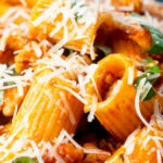 Close-up spicy ground chicken rigatoni with fresh basil and parmesan cheese.
