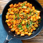 Overhead spicy ground chicken rigatoni with fresh basil in a pan.