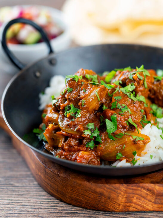 Beef bhuna or bhuna gosht curry with rice, poppadoms and kachumber salad.