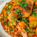 Close-up braised rabbit leg stew with pearl barley, leeks and carrots featuring a title overlay.