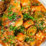 Close-up stewed rabbit with pearl barley, leeks and carrots featuring a title overlay.