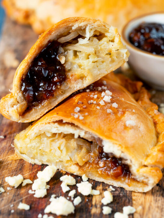 Cheese and onion pasty with Branston pickle cut open to show the filling.