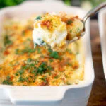 Cheese and breadcrumb topped smoked haddock and potato gratin on a spoon.