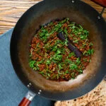 Overhead Indian chicken keema curry with green beans served in a wok.