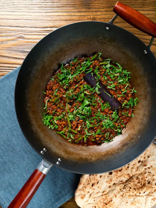 Overhead Indian chicken keema curry with green beans served in a wok.