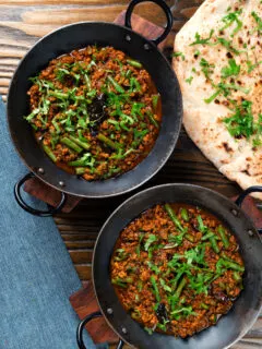 Overhead Indian chicken keema curry with green beans served with naan bread.