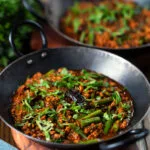 Indian chicken keema curry with green beans served with naan bread.