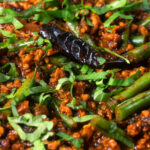 Close-up Indian chicken keema curry with green beans and fresh coriander.