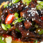 Close-up Chinese takeaway style sticky crispy chilli beef in a sticky sauce.