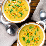 Overhead curried cauliflower veloute soup garnished with turmeric potatoes and coriander.