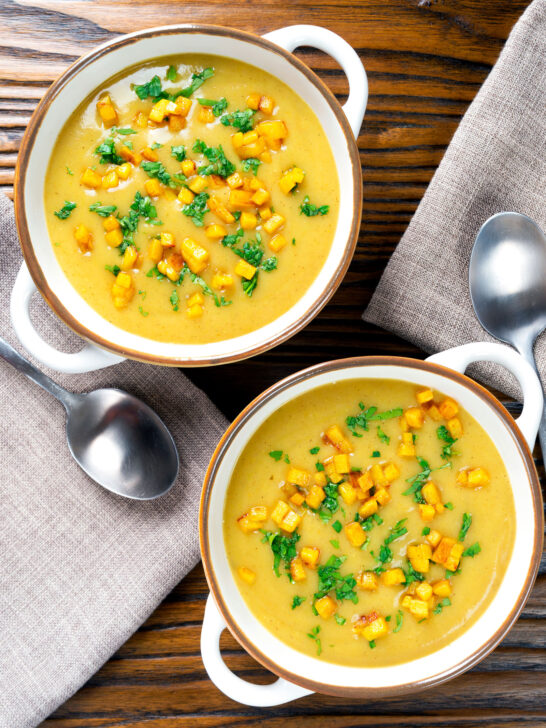 Overhead curried cauliflower veloute soup garnished with turmeric potatoes and coriander.