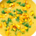 Overhead close-up curried cauliflower veloute soup garnished with turmeric potatoes.