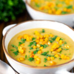 Curried cauliflower veloute soup garnished with turmeric potatoes and coriander.