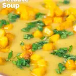 Close-up curried cauliflower veloute soup garnished with turmeric potatoes and coriander featuring a title overlay.