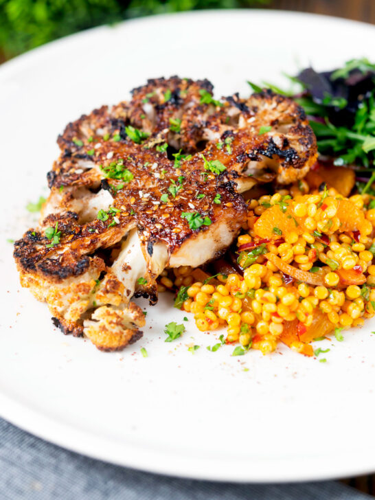 Roasted cauliflower steak served with giant couscous salad.